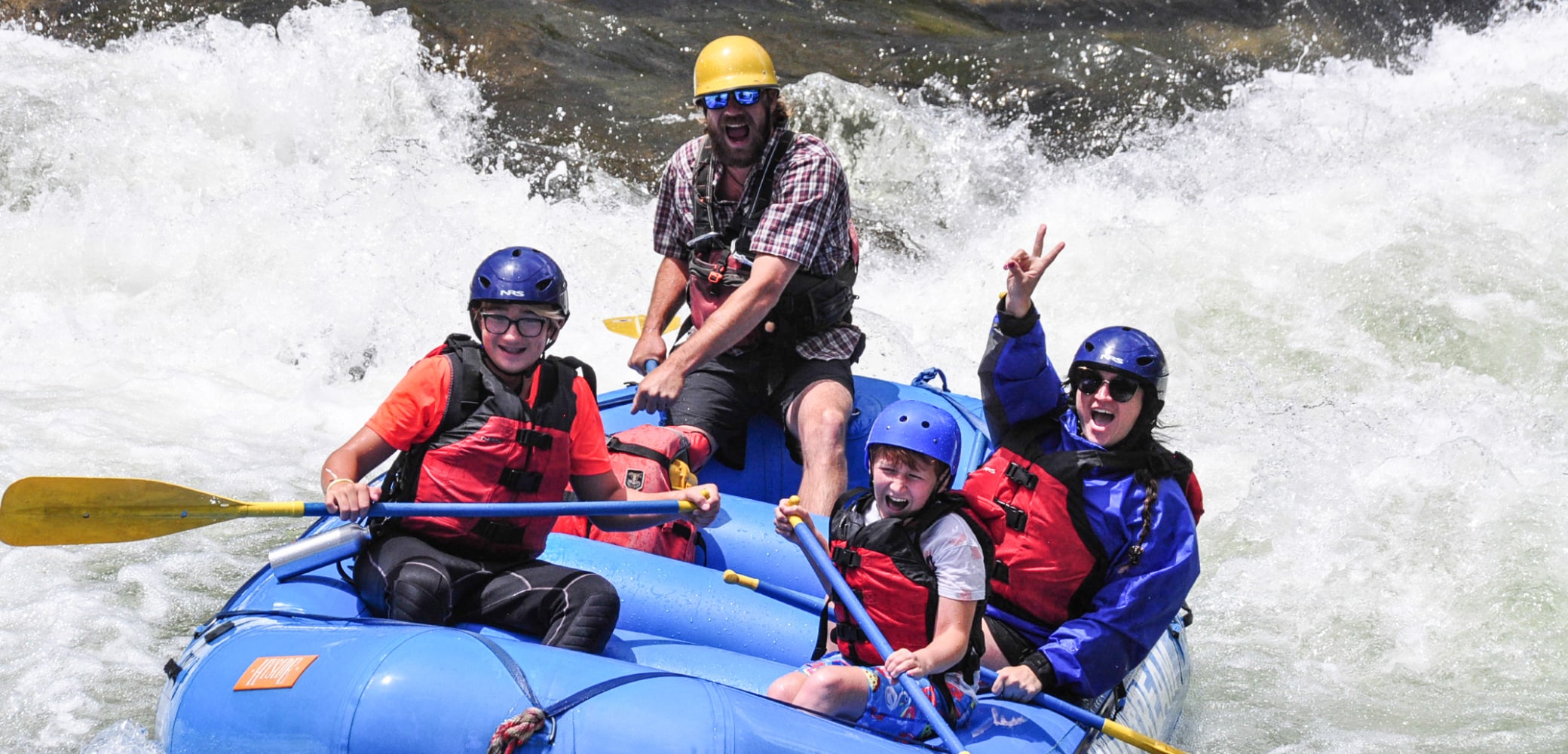 people smiling on raft navigating middle clear creek rapids