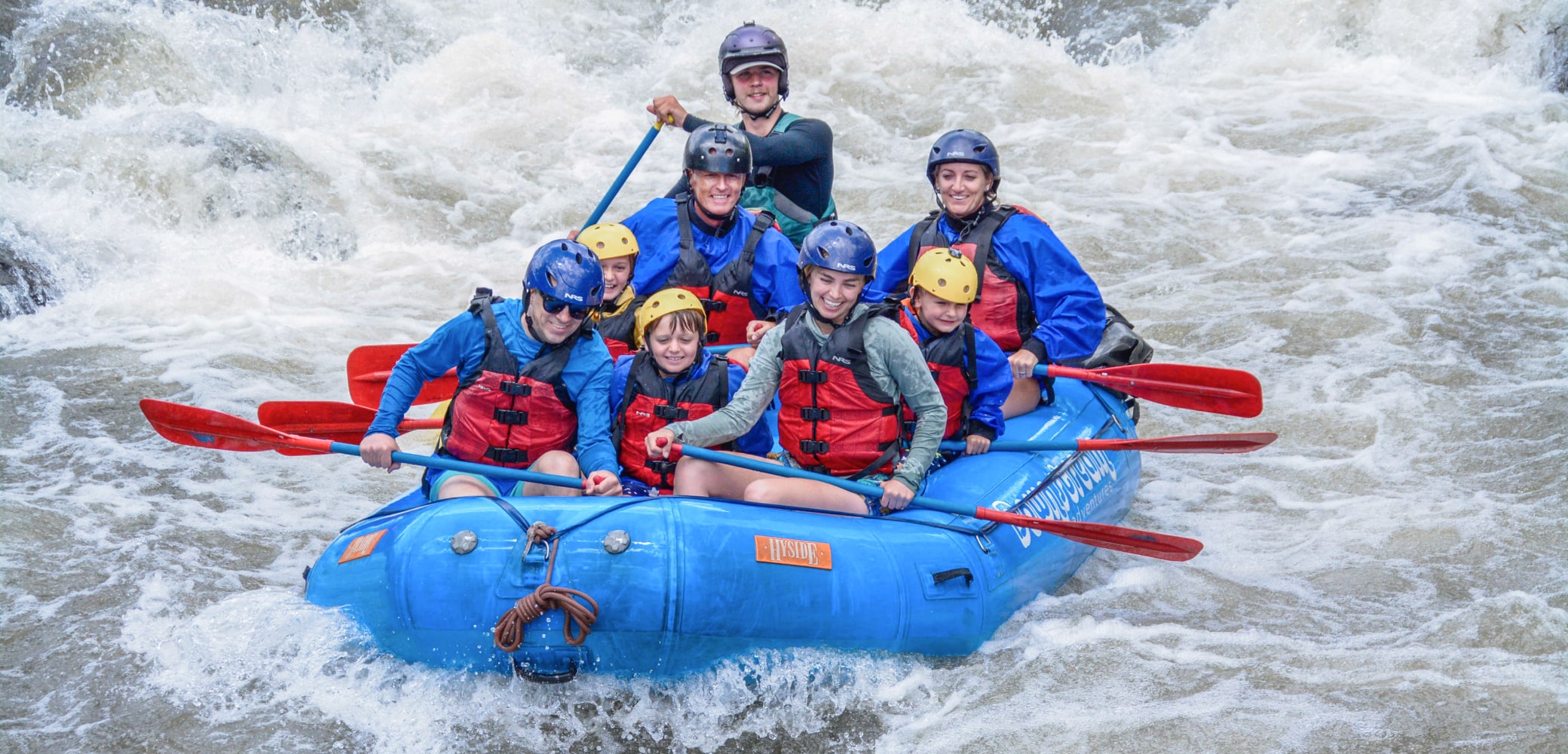 kids and parents smiling while white water rafting on the clear creek in colorado