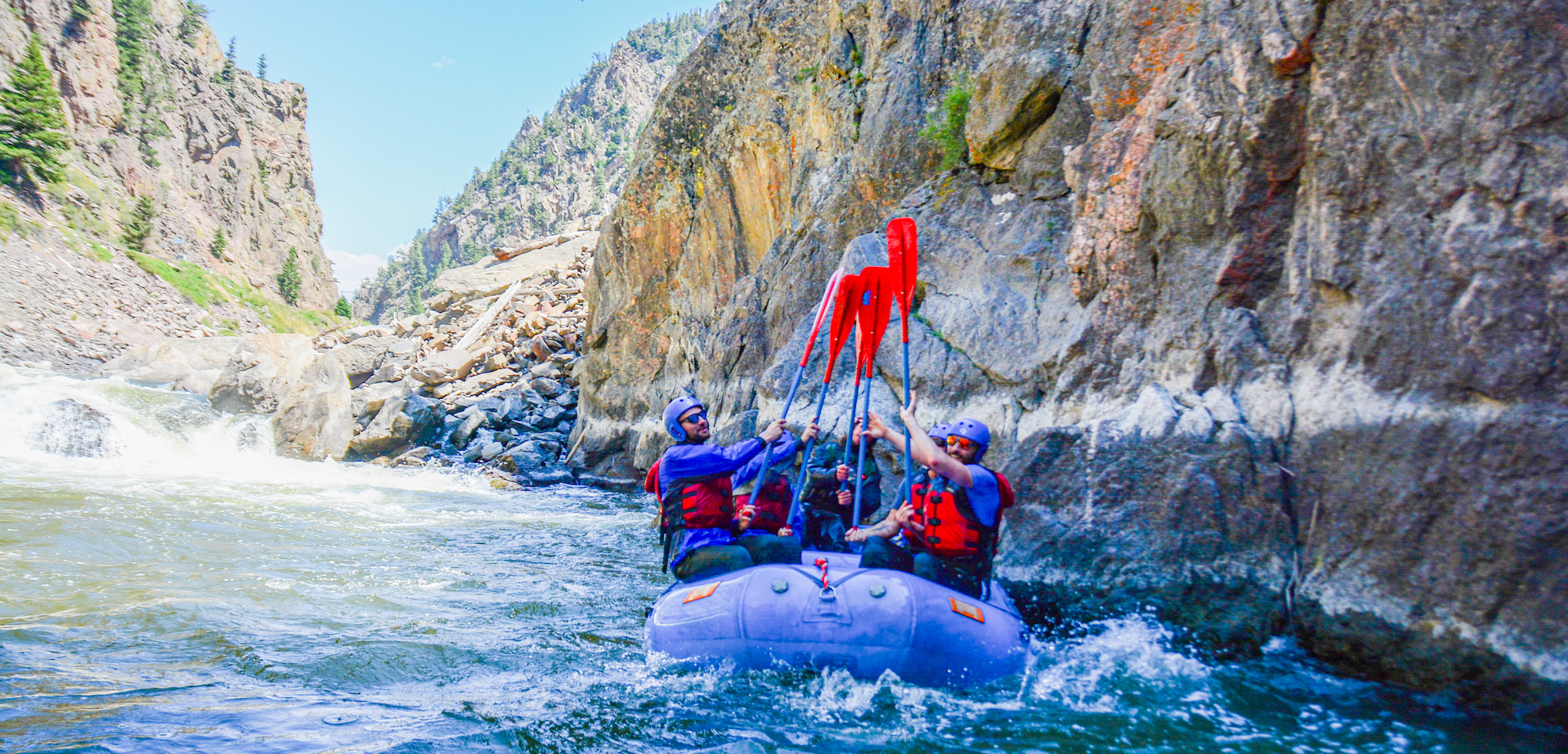 people raising their oars while rafting Gore Canyon Colorado