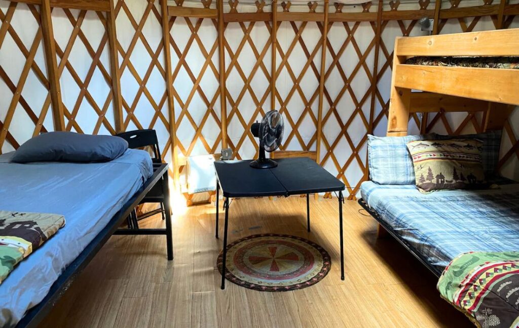 a bunkbed and twin bed with a table in a yurt in Colorado