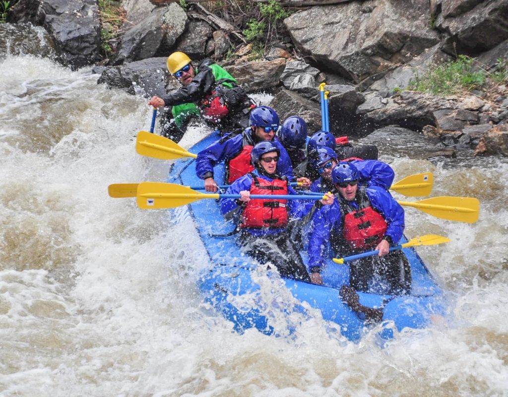 people in a blue raft whitewater rafting near Denver