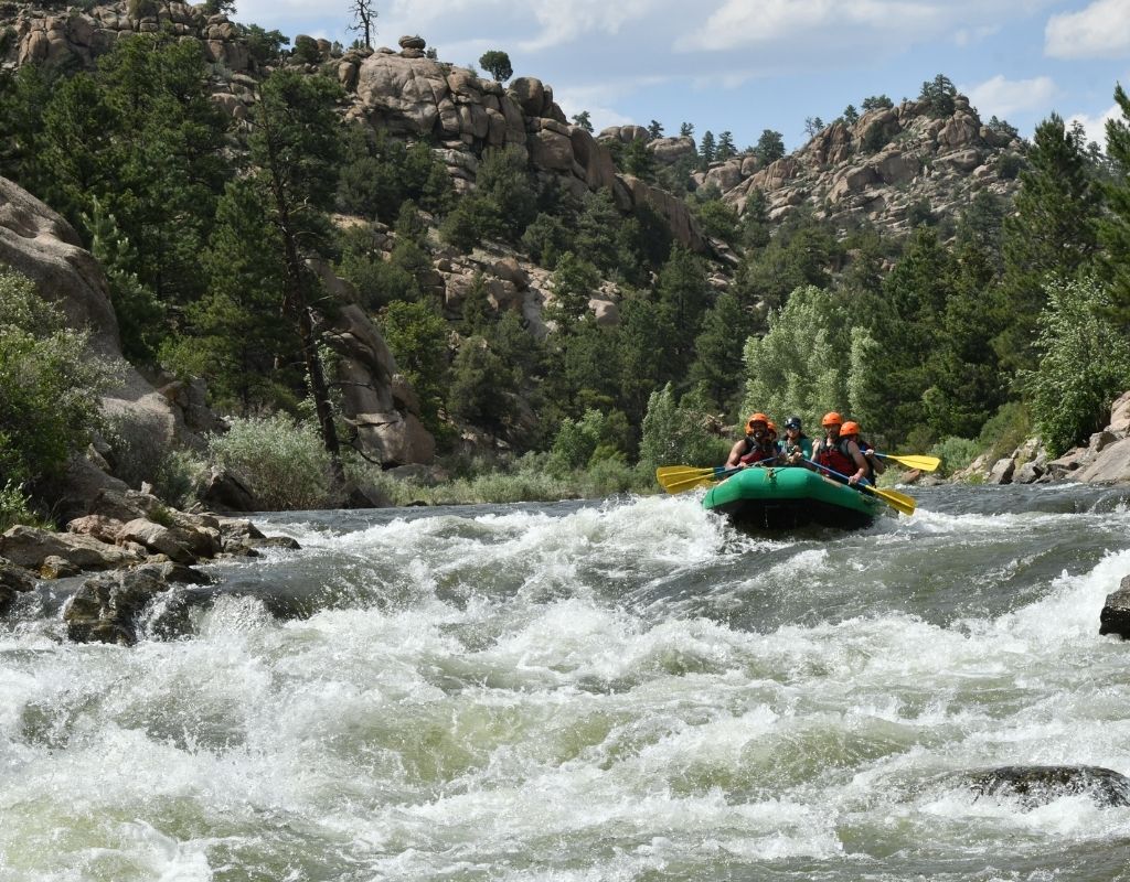 people in a green raft about to reach the rapids while rafting in Buena Vista, CO
