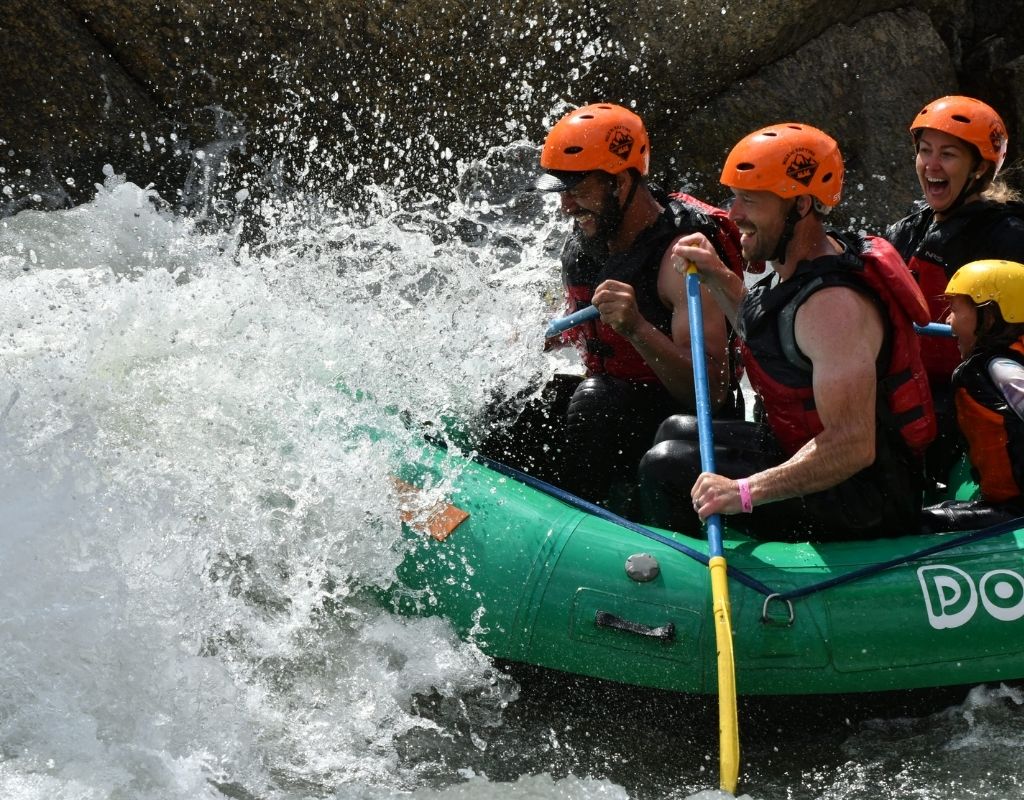 group of people on a green raft in the rapids while whitewater rafting in Salida, CO