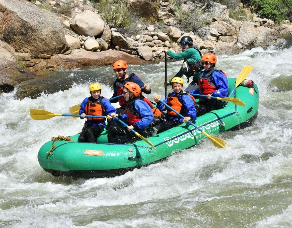 people in a green raft on the rapids of the Arkansas River while rafting near Buena Vista