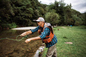 man fly fishing in colorado from river bank